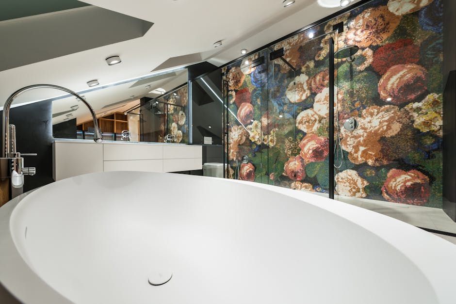 Oval shaped bathtub against shower room with floral ornament on wall in contemporary bathroom with lamps in house