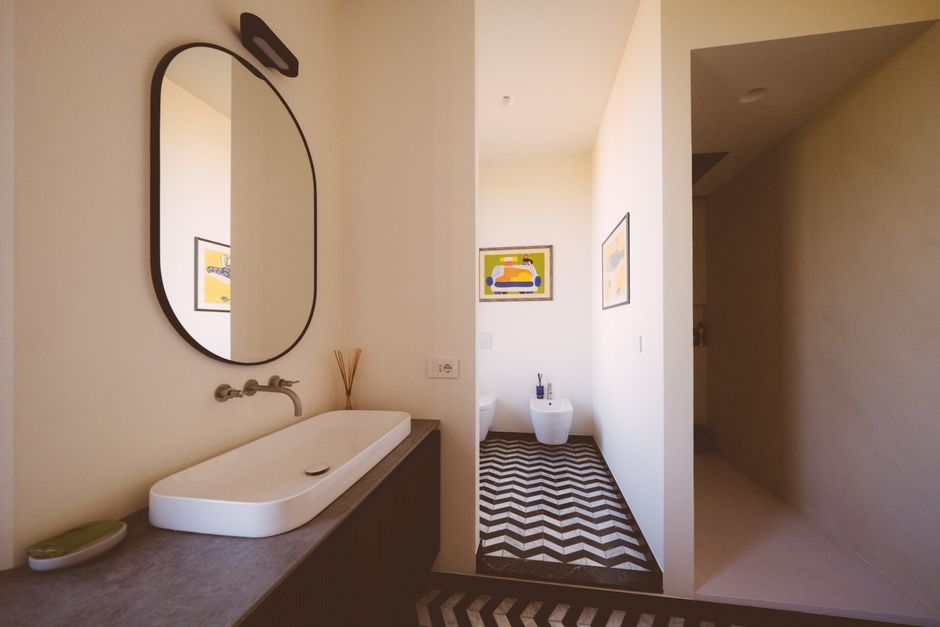 Sleek minimalist bathroom with chevron patterned floor, mirror, and contemporary fixtures.