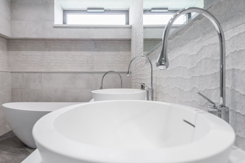 White ceramic sinks and chrome faucets installed in modern bathroom with light gray walls in contemporary luxury house