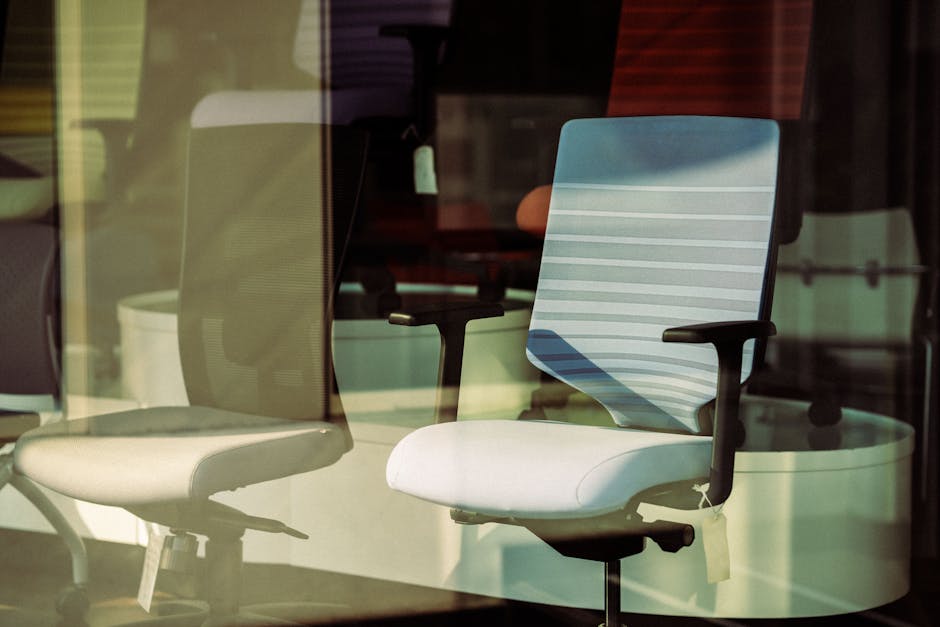 Contemporary office chairs displayed behind glass, offering modern ergonomic solutions for workspace.