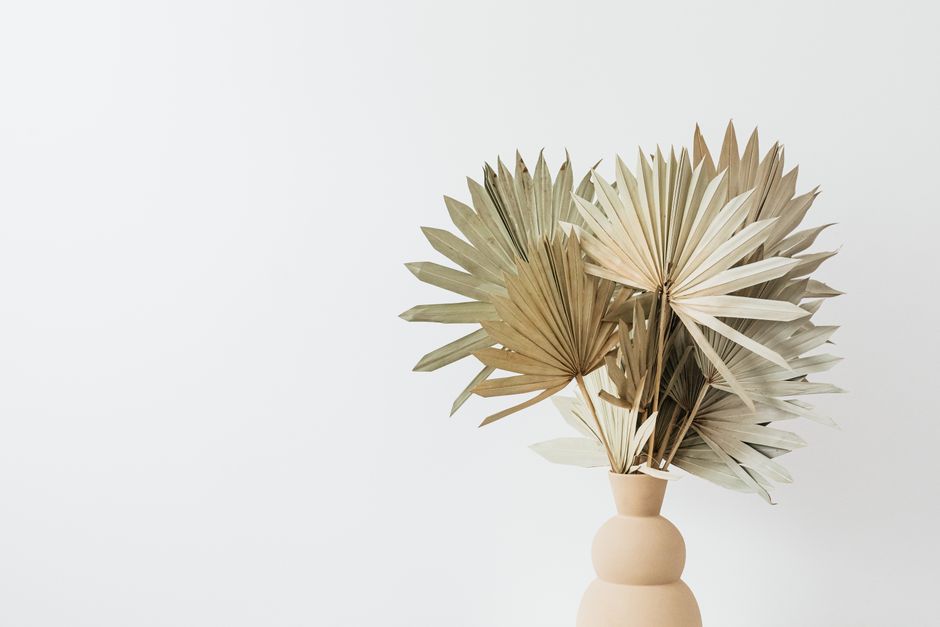 Elegant arrangement of dried palm leaves in a minimalist vase against a white background.