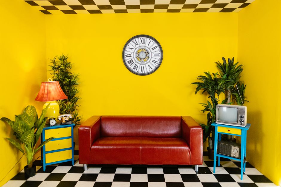 Vibrant yellow room with a red couch, retro decor, and checkered floor.